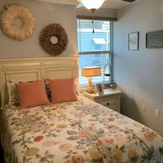 A cozy bedroom with floral bedding and decorative wall art.