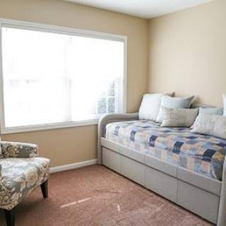 A cozy bedroom with a daybed and a large window letting in natural light.