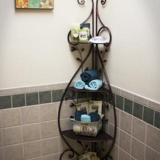 A decorative iron rack holding neatly arranged towels and toiletries in a bathroom corner.