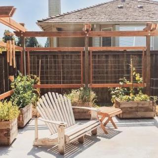 A cozy backyard patio with a wooden chair and planters, perfect for relaxation.