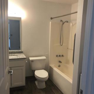 A small bathroom featuring a toilet, bathtub with shower, sink, and mirror.