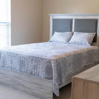 A minimalist bedroom with a neatly made bed and a light quilt.