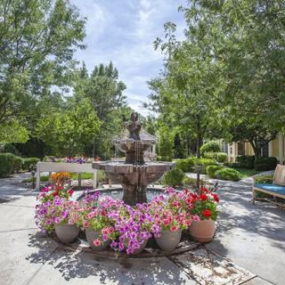 A serene garden scene featuring a central fountain surrounded by vibrant flowers.