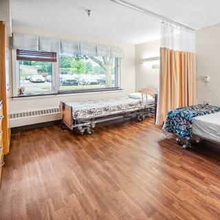 A clean and modern hospital room designed for patient care, featuring two beds and natural light coming through the windows.