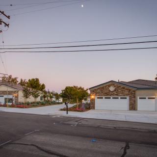 A quiet suburban street at dusk with houses and a visible moon in the sky.