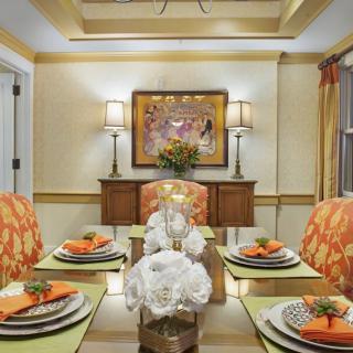 A beautifully decorated dining room with orange accents, elegant floral arrangements, and soft lighting.