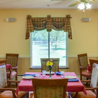 A cozy dining area with a beautifully set table, inviting natural light from the window.