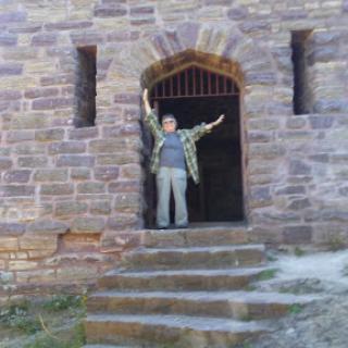 A person joyfully standing in the entrance of a historic stone structure.
