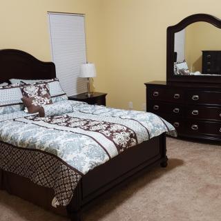 A neatly arranged bedroom with a bed, dresser, and mirror.