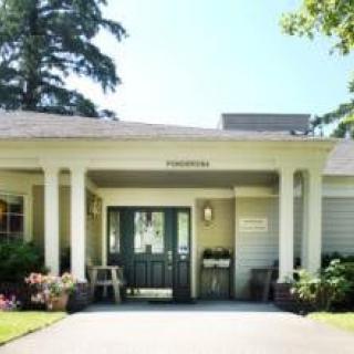 A welcoming entrance with columns and greenery surrounding a residential building.