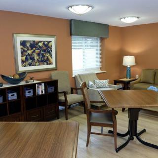 A cozy living room with comfortable seating, artwork on the wall, and a lamp providing soft lighting.