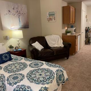 A cozy bedroom with a beautifully patterned bedspread, a comfortable sofa, and elegant wall art.