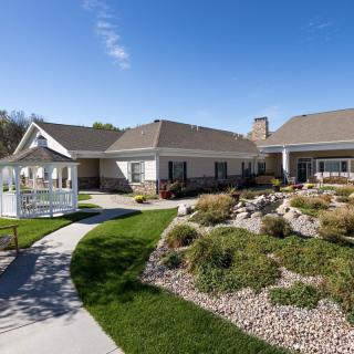 A beautiful house with a landscaped garden and a gazebo under a clear blue sky.