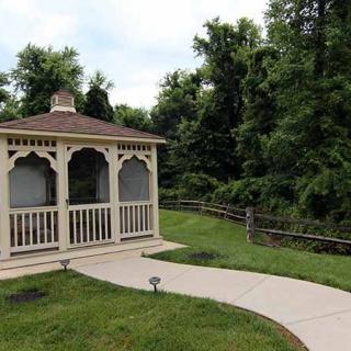 A charming gazebo situated along a curved pathway in a lush garden setting.
