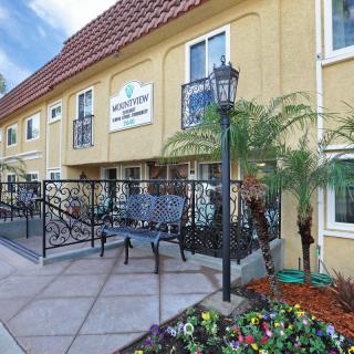 A charming hotel exterior with lush landscaping and outdoor seating.
