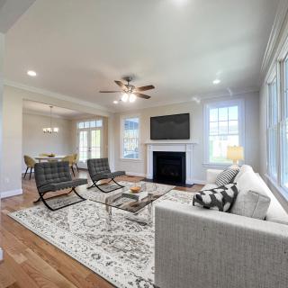 A modern living room with stylish furniture, featuring a sofa, two chairs, a coffee table, and a fireplace under a wall-mounted TV.