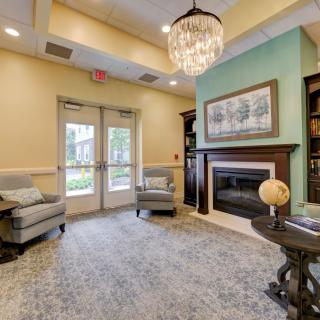 A cozy lobby area featuring plush chairs, a chandelier, and a fireplace, creating an inviting atmosphere.