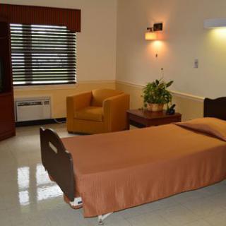 A hospital room with a bed, chair, and television.