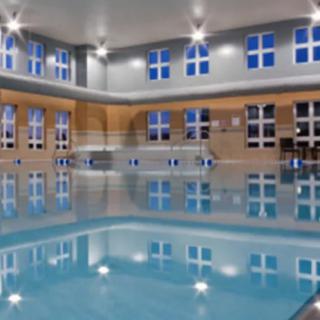 A luxurious indoor swimming pool area with large windows and ambient lighting.