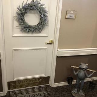 A decorated door with a wreath and a frog statue in the hallway.