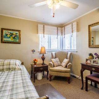 A cozy, traditional bedroom with a comfortable chair, bed, and decorative elements.