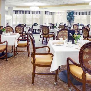 An elegant dining room with neatly arranged tables and chairs, set for a meal.