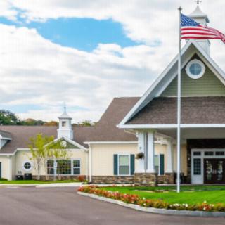 A picturesque building with an American flag in front, surrounded by well-maintained landscaping under a blue sky.