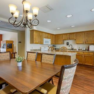 A spacious kitchen and dining area featuring wooden cabinets, a large table with cushioned chairs, and a decorative chandelier.