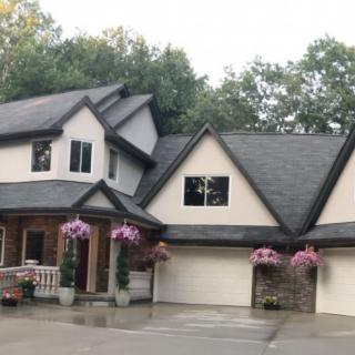 A large two-story house with decorative flowers and a spacious driveway.