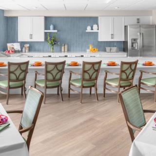 A modern kitchen and dining area featuring white cabinets, a large countertop, and decorative chairs.