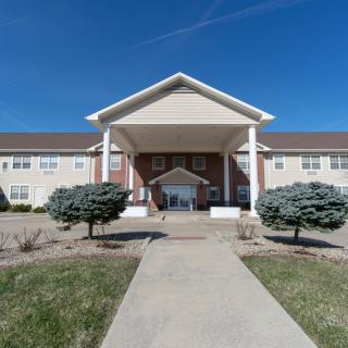 A two-story building with a prominent entrance featuring large columns and a clear blue sky above.