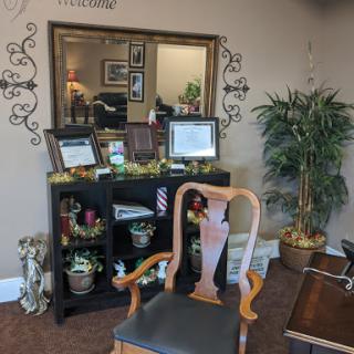 A cozy corner of an office featuring a decorative mirror, plants, and a comfortable reading chair.