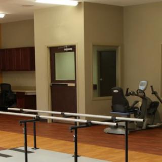 A rehabilitation facility with exercise equipment and parallel bars.