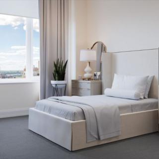 A modern, minimalist bedroom with a single bed and elegant decor.