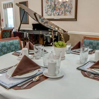An elegantly set dining table with a piano in the background.