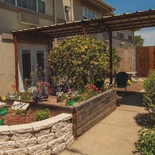 A cozy backyard featuring a pergola-covered patio and a variety of plants in raised garden beds.