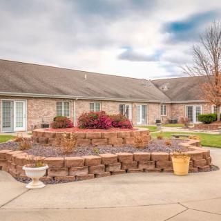 A brick building with a landscaped courtyard featuring potted plants under a cloudy sky.