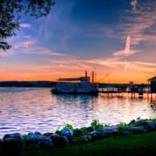 A peaceful lake scene at sunset with a boat near the pier.