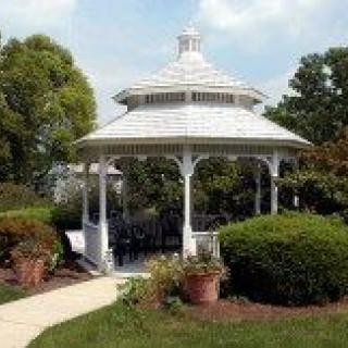 A charming white gazebo surrounded by lush greenery in a serene park setting.