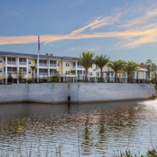 A waterside building with palm trees at sunset.