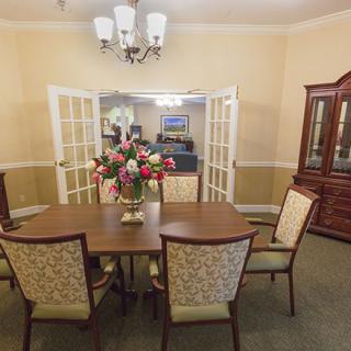 A well-decorated dining room with a wooden table, chairs, and a chandelier overhead.