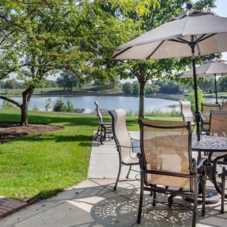 A scenic outdoor patio with tables and umbrellas overlooking a tranquil lake.