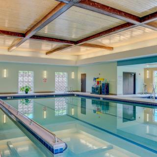 A well-lit indoor swimming pool with modern design and large windows.