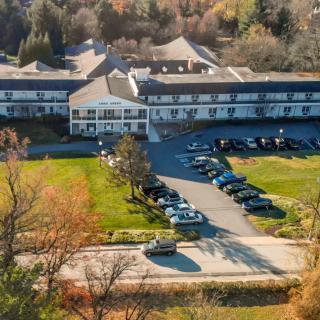 Aerial view of a large building with a parking lot surrounded by autumn foliage.