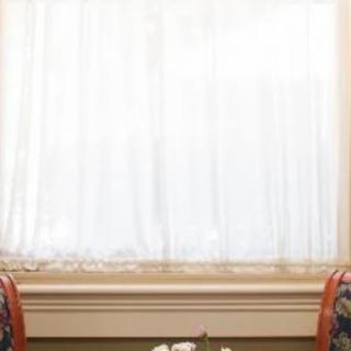 A cozy setting with two chairs facing a table, framed by a window with white curtains.