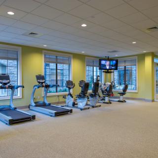 A modern gym with treadmills and stationary bikes in a bright, spacious room.