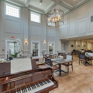 An elegant dining area with a grand piano and chandelier.