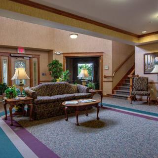 A cozy lobby area featuring a sofa, tables, and decorative plants.