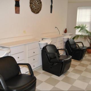 An interior view of a hair salon with black chairs and washing stations.