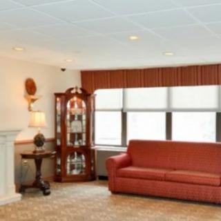 A cozy living room with a red sofa, large windows, and a glass cabinet.